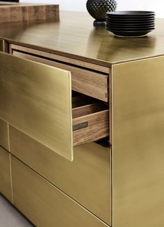 a gold dresser with drawers and plates on top