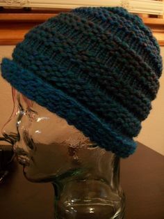 a knitted blue hat on top of a glass mannequin's head