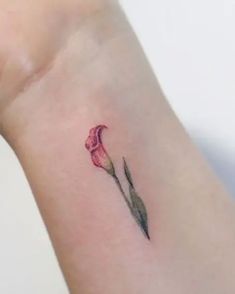 a small pink flower tattoo on the wrist