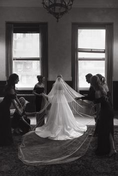 the bride is getting ready to walk down the aisle with her veil in hand and three other women around her