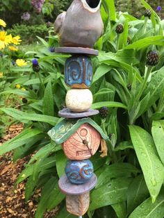 a birdhouse made out of rocks sitting on top of green leaves and flowers in the background