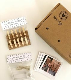 some clothes pins are sitting on a table next to an open box and two photos