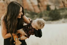 a woman holding a small boy in her arms and smiling at the camera while he holds him