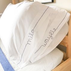 four pillows stacked on top of each other in front of a wooden bed frame with blue and white sheets