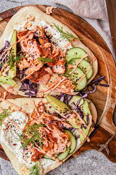 two flatbreads topped with chicken, cucumber and onions on a wooden platter