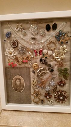 a white frame with many different pieces of jewelry in it