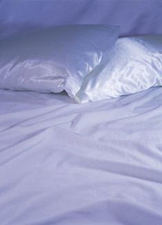 two white pillows sitting on top of a bed