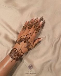 a woman's hand with henna tattoos on it, laying on a bed