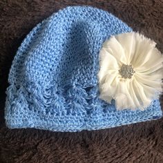 a crocheted hat with a white flower on the front and blue brim