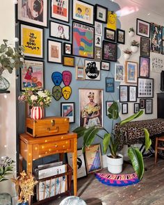 a living room filled with lots of pictures on the wall and plants in vases