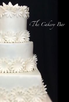 a three tiered cake with white flowers on it