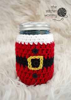 a mason jar with a red and white crochet pattern on it sitting on a fluffy surface