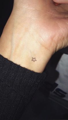 a woman's wrist with a small star tattoo on the left side of her arm