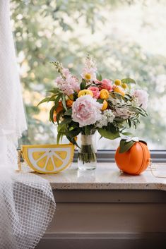 a vase filled with flowers sitting on top of a window sill next to an orange slice