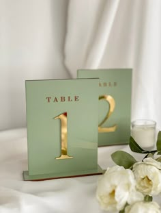 there are two tables that have flowers and candles on the tablecloth, one is green with gold numbers