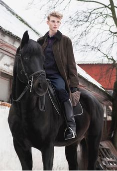 a young man riding on the back of a black horse