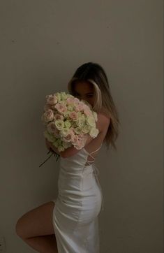 a woman in a white dress holding a bouquet of flowers