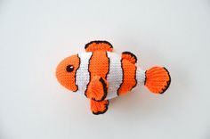 an orange and white crocheted clown fish sitting on top of a white surface