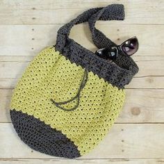 a crocheted bag sitting on top of a wooden floor next to some sunglasses