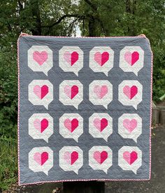 a gray and pink quilt with hearts on it