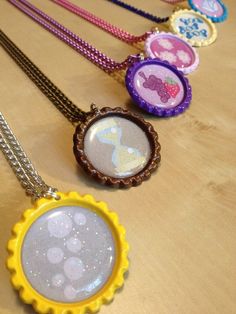 several necklaces with different designs on them sitting next to each other in front of a wooden table