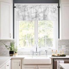 a kitchen with white cabinets and marble counter tops on the window sill above the sink