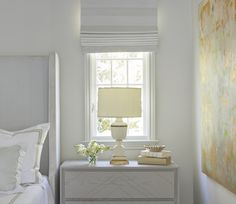 a bedroom with a white bed, nightstand and window