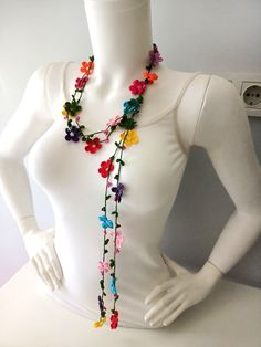 a white mannequin wearing a multicolored flower necklace on it's neck