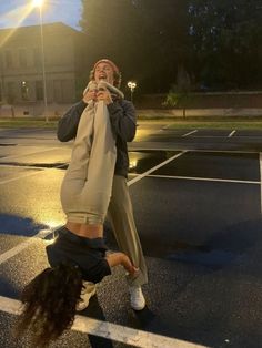 a person doing a handstand in the middle of a parking lot at night