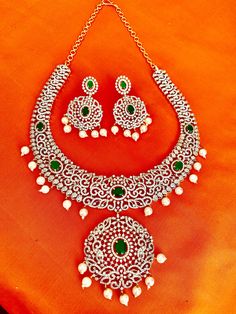 This stunning CZ American Diamond South Indian Haaram is a perfect addition to your collection. Featuring green stones and a medium size, it is ideal for both weddings and parties. It also makes a great gift for her. Elevate your Indian outfit, whether it's a silk saree or a gown, with this elegant piece. This jewellery set includes a necklace, matching earrings. Jewellery Care- Keep the jewellery dry, avoid contact with perfumes and water. Emerald Stone Necklaces For Weddings, Cubic Zirconia Bridal Necklace With Stones For Wedding, Green Sparkling Stones Jewelry For Anniversary, Elegant Diamond Bridal Sets With Stone Work, Dazzling Stone Wedding Jewelry, Wedding Bridal Necklace With Cubic Zirconia Stones, Dazzling Wedding Jewelry With Stones, Diamond Bridal Necklace With Stone Work For Parties, Elegant Green Jewelry With Stone Work