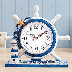 a blue and white clock sitting on top of a wooden table next to a lighthouse