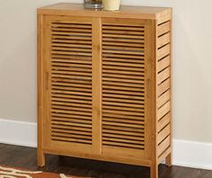 a wooden cabinet sitting on top of a hard wood floor next to a white wall