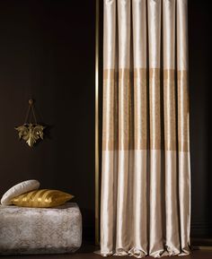 a bed sitting under a window next to a gold wall mounted clock on a wall