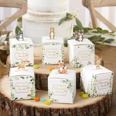 small boxes with animals on them sitting on a tree stump in front of a wedding cake