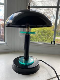 a black lamp sitting on top of a table next to a window