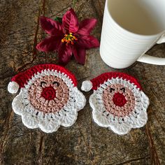 two crocheted santa claus coasters next to a coffee cup