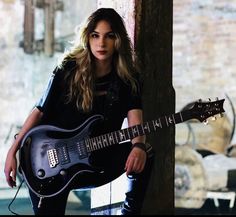 a woman with long hair holding a guitar