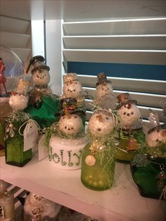 snowmen are sitting on top of green bottles and candles in the shape of snowmen