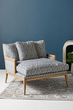 a living room with blue walls and a gray patterned chair next to a small fireplace