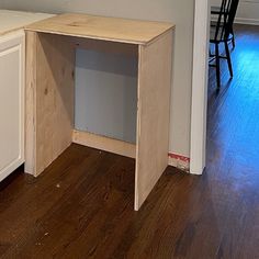 an unfinished desk sits in the middle of a kitchen with white cabinets and wood floors