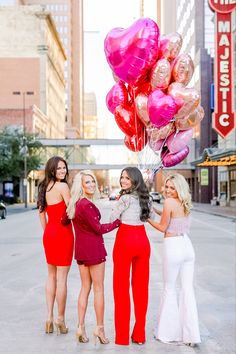 three women in red dresses holding pink and gold balloons