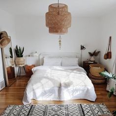 a bedroom with a bed, rugs and potted plants on the floor in front of a window