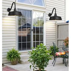 an outdoor patio with potted plants and two lights on the side of the house