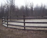 a fenced in horse paddock with trees in the background