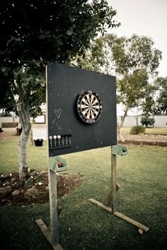 a dart board with darts on it in the middle of a field next to a tree