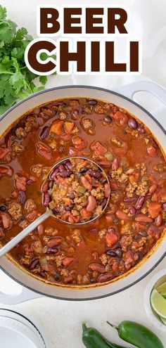 a large pot filled with chili and beans on top of a white table next to limes