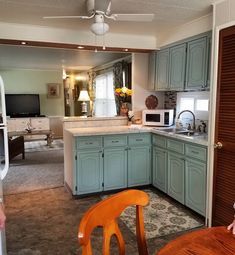 a kitchen with blue cabinets and white counter tops in an open floor plan, along with a dining room table