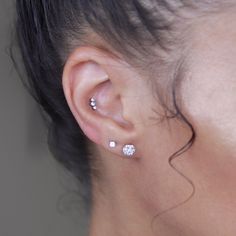 a close up of a person's ear with two piercings on it and one behind the ear