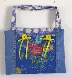 a blue bag with yellow handles and flowers painted on the side, hanging from a wall