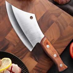 a large knife sitting on top of a cutting board next to sliced tomatoes and garlic